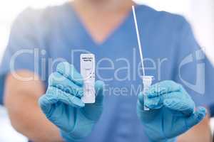 Unrecognizable doctor wearing gloves holding a covid test and a cotton swab while working alone at a hospital. One unrecognizable nurse working with a cotton swab and covid test at a clinic