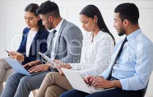 Group of diverse businesspeople waiting for interview and using technology. Team of young applicants sitting together. Professional candidates in line for job opening, vacancy and office opportunity