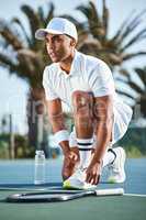 Staying focused, always. Full length shot of a handsome young man kneeling down to tie his shoelaces before tennis practice.