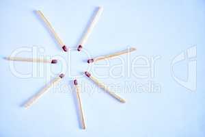 Seven matchsticks arranged in a circle in studio isolated against a blue background. All it takes is a spark to ignite and burst into flames. All you need to start a fire to keep warm during winter