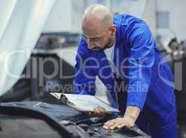 Making sure everything is up to standard. a handsome young male mechanic working on the engine of a car during a service.