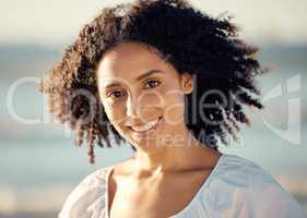 Portrait of a happy young mixed trace woman face with a curly afro, beautiful hispanic woman enjoying some time at the beach. Closeup shot of a smiling young female having fun on a weekend