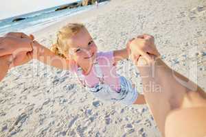 Father spinning daughter, having fun on the beach. A cute smiling little girl playing with her parent on vacation. Fun family vacation