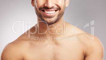 Closeup young mixed race man shirtless in studio isolated against a grey background. Hispanic well groomed male looking confident and happy with his oral and dental hygiene. Mouth and gum health