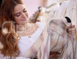 Im really considering this one. an attractive young woman checking an item of clothing in a store.