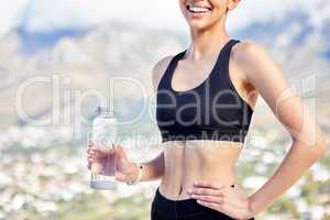 Closeup of one fit mixed race woman taking a rest break to drink water from bottle while exercising outdoors. Female athlete quenching thirst and cooling down after running and training workout