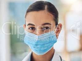 Young female mixed race nurse wearing a mask to protect herself from covid disease while working at a hospital. Portrait of a young female hispanic doctor standing at a clinic