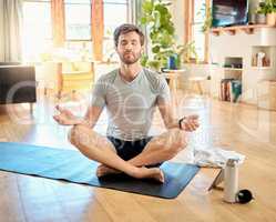 One young caucasian man sitting with legs crossed and eyes closed meditating in harmony with om finger gesture while practising yoga at home. Calm, relaxed and focused guy feeling zen while praying quietly for stress relief and peace of mind