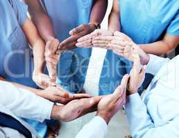 Just go with the flow. Shot of a group of unrecognizable doctors making a circle shape with their hands at work.
