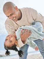 Smiling mixed race single father carrying little daughter on the beach. Adorable, happy, latin girl bonding with parent and playing on beach. Man and cute child enjoying free time