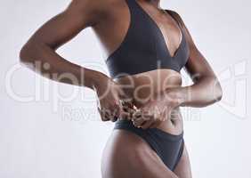 I didnt come this far just to come this far. Studio shot of a woman pulling the skin on her outer waist.