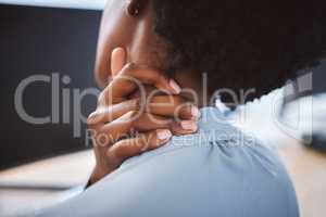 Closeup of one stressed african american businesswoman suffering with neck pain in an office. Entrepreneur rubbing muscles and body while feeling tense strain, discomfort and hurt from bad sitting posture and long working hours at desk