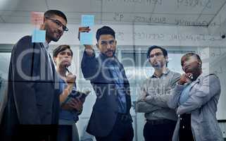 Combining our mental brilliance. Shot of a team of business people brainstorming ideas together using sticky notes.