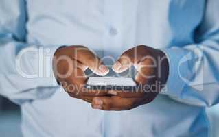 Closeup hands of african man using a phone while standing in his office. African american business man sending a text message while working late at night at his work. Putting in overtime after hours