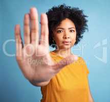 Youve gone far enough. Shot of an attractive young woman standing alone against a blue background in the studio and showing a stop gesture.