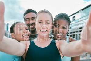 Portrait of a diverse group of happy sporty people taking selfies while exercising together outside. Cheerful motivated athletes excited and ready for training workout. Supportive friends taking photos for social media