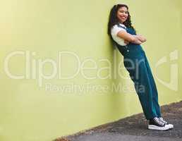 Fullbody beautiful mixed race fashion woman smiling with her arms crossed against a lime green wall background in the city. Young happy hispanic woman looking stylish, trendy. Carefree and fashionable