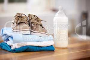 Just waiting for our little boy. baby clothes and a milk bottle on a table at home.