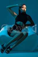 Shes a woman of style. Conceptual shot of a stylish young woman posing in studio against a blue background.