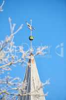 Spire of the church above the trees. Church spires against the cloudy sky in a blue sky. Close up of a spire in an autumn season with a clear sky in the background. A branch of a tree without leaves.