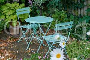 Chairs and a table with blossoming plants in a park or private patio outdoors. Empty seating in a lush green garden to relax and enjoy a picnic or fresh and stressless day in nature during spring
