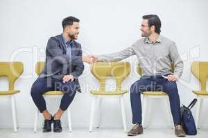 Making friends in the waiting room. Shot of two businessmen shaking hands while waiting to be interviewed.