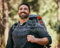 One happy mature caucasian man carrying a backpack and hiking alone in the woods during the day. Smiling fit and active man enjoying nature while exercising and exploring. Staying active on adventures