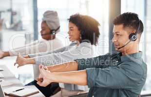 Group of call centre telemarketing agents stretching their arms while working together in an office. Hispanic male consultant taking a break to get ready to operate helpdesk for customer service and sales support