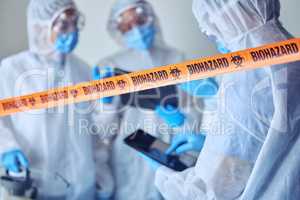 Closeup of biohazard tape blocking of prohibited area. Team of scientists cleaning prohibited area. Medical csi team using a digital tablet in quarantine area. Biologist using wireless device