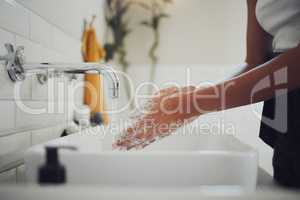 Close up of female hands using soap and washing hands with clean water under tap. Woman lathering and rinsing to prevent the spread of germs, bacterial infections