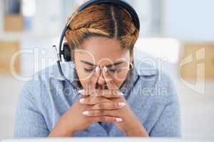 Stressed young mixed race female call centre agent getting a headache while working in office. Consultant making mistakes and struggling with difficult customers when operating a support helpdesk