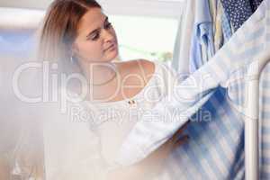 I love the quality of the items here. an attractive young woman checking an item of clothing in a store.