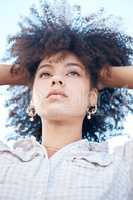 Closeup shot of a beautiful young mixed race female with her hands in her afro. Below shot of one african american woman looking thoughtful and contemplative while standing outside. Full of ideas