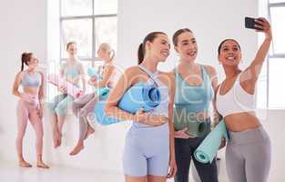 Happy friends taking a selfie before yoga class. Group of women taking a photo on a cellphone before pilates class. Young women bonding before an exercise class. Women using cellphone in yoga class