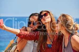 Strike your best pose. three best friends taking selfies together using a smartphone.