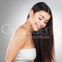 Shes got it. Studio shot of a beautiful young woman showing off her long silky hair against a grey background.