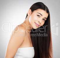 Watch in awe as she unfolds. Studio portrait of a beautiful young woman showing off her long silky hair against a grey background.