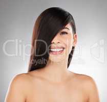 Do it at your level. Studio portrait of a beautiful young woman showing off her long silky hair against a grey background.