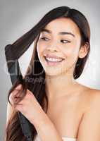 Ill use my last strength to style my hair. Studio shot of a beautiful young woman styling her hair against a grey background.