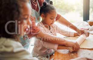 Females only, happy mixed race family of three cooking in a messy kitchen together. Loving black single parent bonding with her daughters while teaching them domestic skills at home