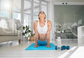 Feel your muscles loosen and ease your tension. a sporty young woman doing an upward facing dog pose while practising yoga at home.