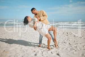 Loving young mixed race couple dancing on the beach. Happy young man and woman in love enjoying romantic moment while on honeymoon by the sea