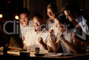 Everything worked out perfectly in the end. a group of businesspeople cheering while working together on a computer in an office at night.