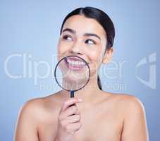 A beautiful mixed race woman posing with a magnifying glass. Young hispanic obsessed with oral hygiene against a grey copyspace background