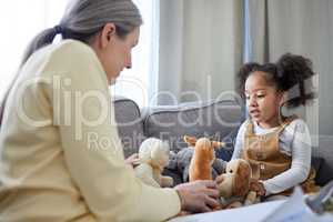 Toys make role play easier. a mature therapist encouraging her young patient to play with toys.