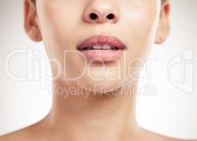 Face of a beautiful woman showing her lips and teeth posing against a grey studio background. Skincare is important. Taking care of dental hygiene