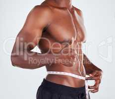 One unrecognizable African American fitness model posing topless with tape measure around his waist . Confident male athlete isolated on grey copyspace showing thumbs up to weight loss