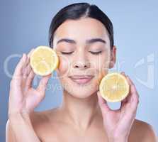 A happy smiling mixed race woman holding a lemon. Hispanic model promoting the skin benefits of a healthy diet against a blue copyspace background