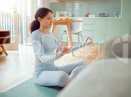 Beautiful young mixed race woman meditating in the asana position while practicing yoga at home. Hispanic female exercising her body and mind, finding inner peace, balance and clarity