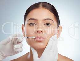 Closeup portrait of woman getting lip fillers or botox. Young caucasian model isolated against grey studio background with copyspace. Dermatologist injecting patient in anti ageing cosmetic procedure